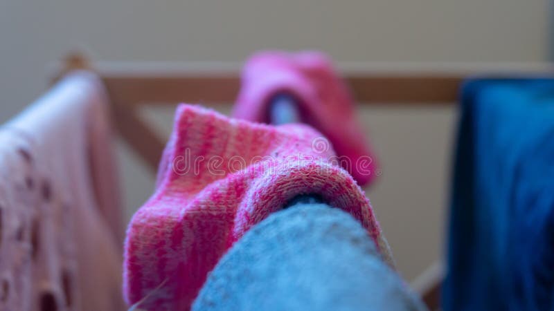 Macro photography close up shot of woven pink magenta ankle sock drying on a laundry rack indoors. Background blur, center