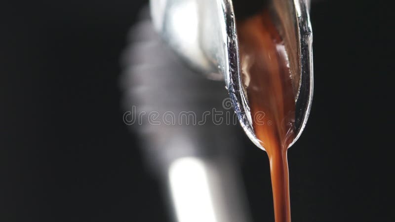Macro shot of coffee extraction and pour from professional coffee machine over black background stock video footage