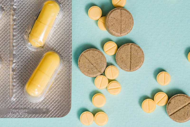 Macro shot detail of yellow oval tablet pills with blister packs on white b...
