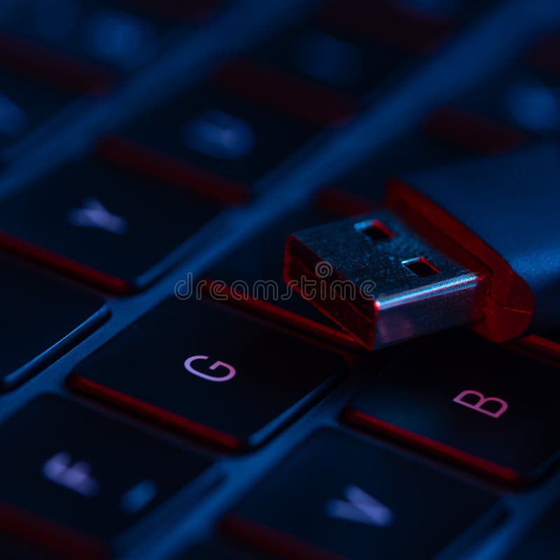 Macro shot of flash drive on a laptop keyboard with neon lights. Close-up view. Concept of modern technology..