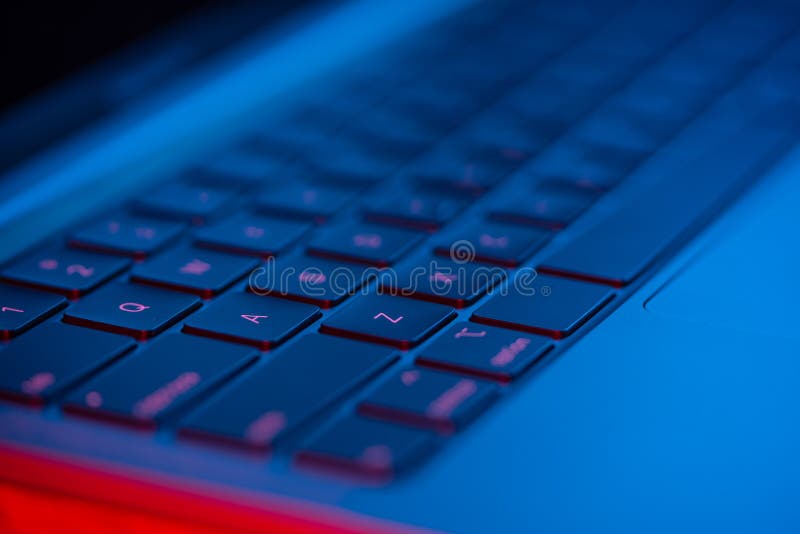 Macro shot of a laptop keyboard with neon lights. Close-up view. Concept of modern technology.