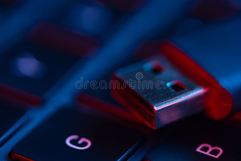 Macro shot of USB flash drive on a laptop keyboard with neon lights. Close-up view. Concept of modern technology.