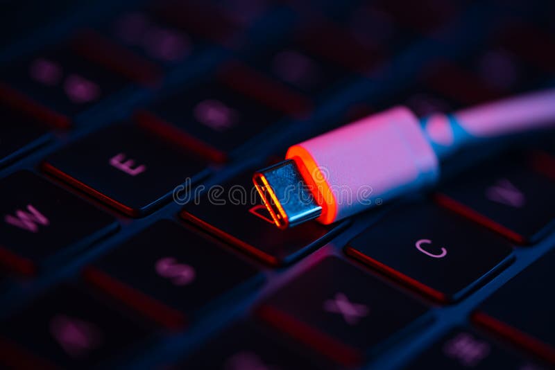 Macro shot of USB switch on a laptop keyboard with neon lights. Close-up view. Concept of modern technology.