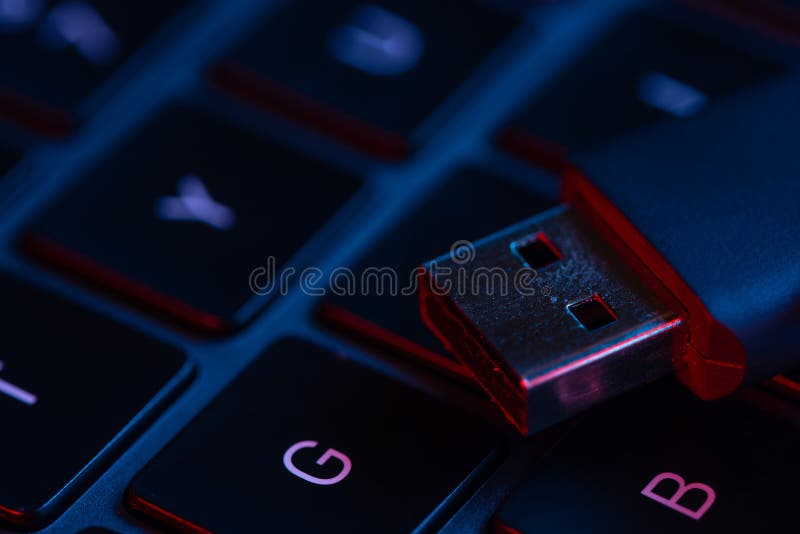 Macro shot view of flash drive on a laptop keyboard with neon lights. Close-up view. Concept of modern technology..