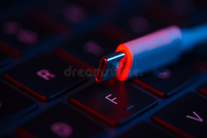 Macro shot view of USB switch on a laptop keyboard with neon lights. Close-up view. Concept of modern technology..