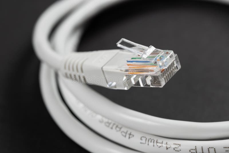 Macrocomandă de închidere a unui cablu Ethernet RJ45 alb pe o masă întunecată stock photos