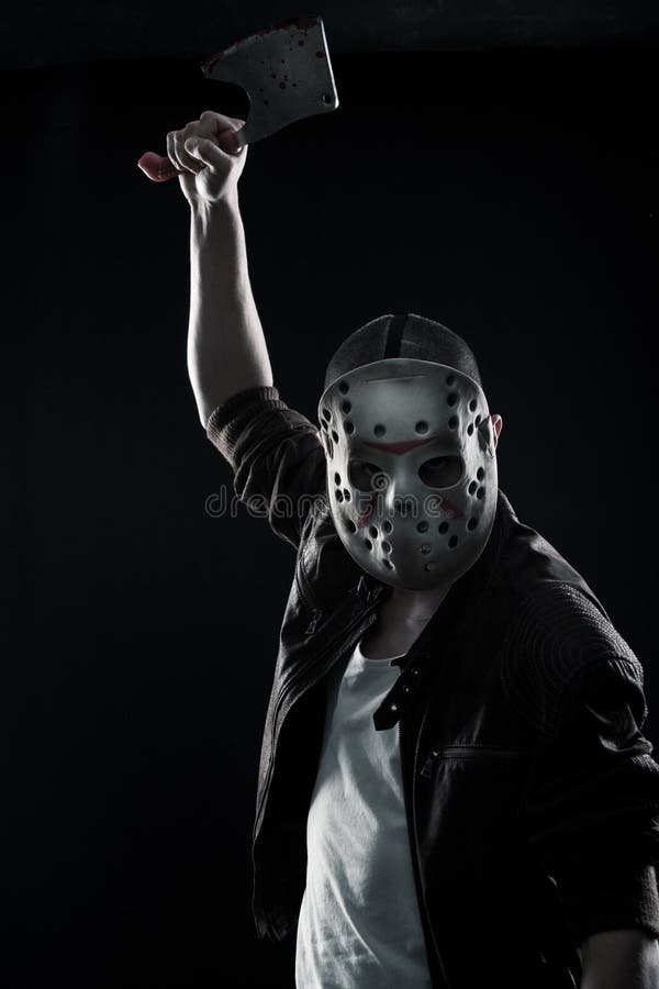 Horrible maniac with bloody chopper posing over dark background stock photo...