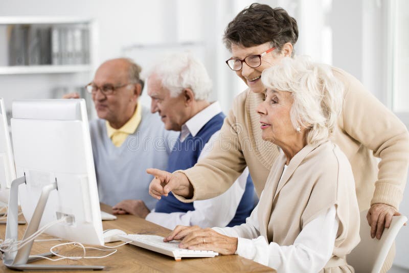 Elder lady with glasses helping her friend with computer issue. Elder lady with glasses helping her friend with computer issue