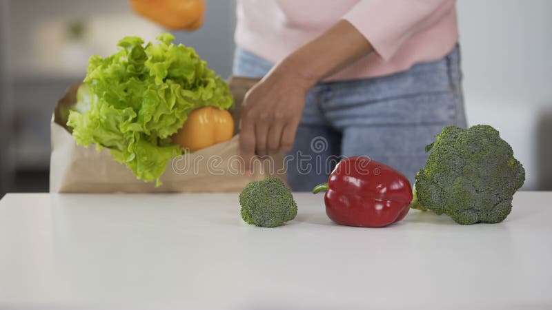 Madame prenant des légumes du sac d'épicerie, mettant sur la table, consommation saine, régime