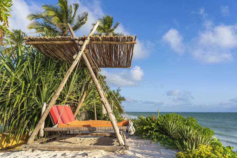 Wooden swing with a mattress under a canopy on the tropical beach near sea, island Zanzibar, Tanzania, East Africa, travel and vacation concept. Wooden swing with a mattress under a canopy on the tropical beach near sea, island Zanzibar, Tanzania, East Africa, travel and vacation concept