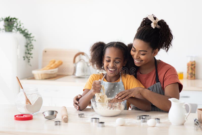 Madre afroamericana enseñando a su hijo adolescente a hornear galletas
