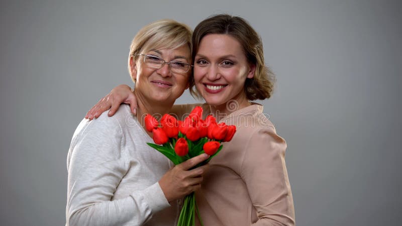 Madre alegre e hija que sonríen y que miran la cámara, sosteniendo tulipanes fotos de archivo libres de regalías Madre alegre e hija que sonríen y que miran la cámara, sosteniendo tulipanes fotos de archivo libres de regalías