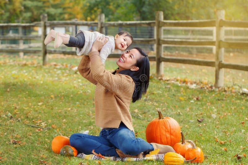 Madre asiatica cinese che tiene per mano una adorabile bimba in un parco autunnale all'aperto fotografie stock Madre asiatica cinese che tiene per mano una adorabile bimba in un parco autunnale all'aperto fotografie stock
