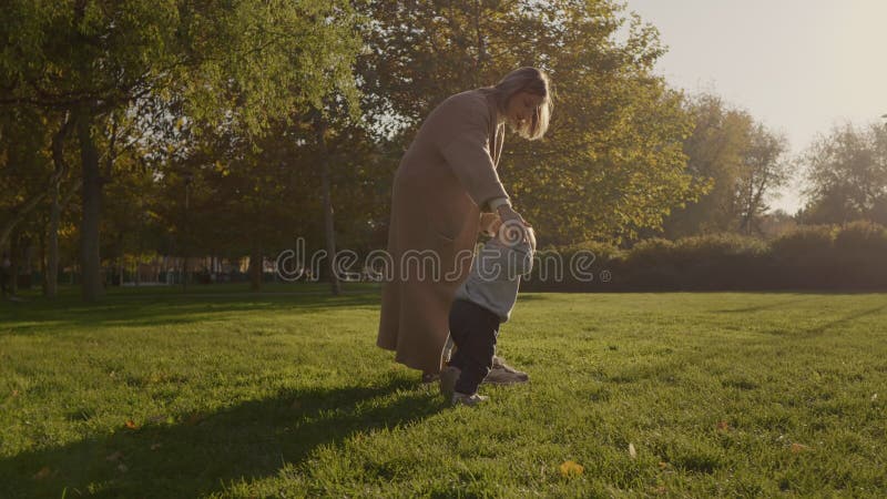 Madre ayudando a su bebé a aprender a caminar en un parque almacen de video