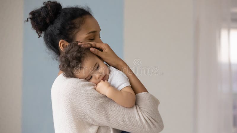 Madre birracial que se preocupa abraza a un bebé pequeño