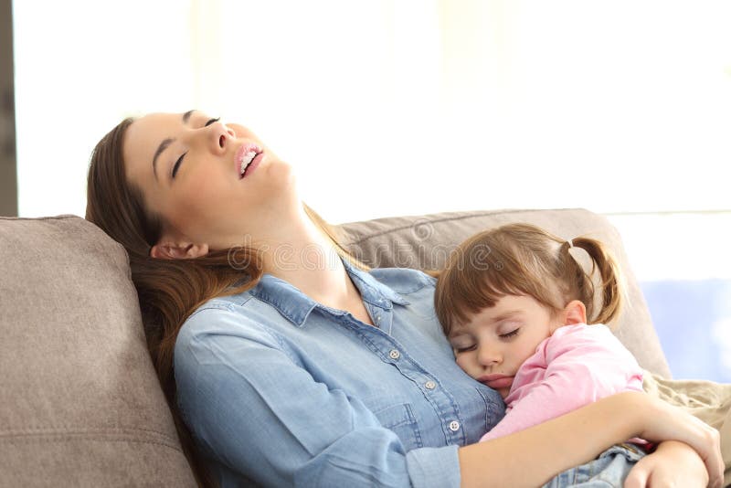 Madre cansada que duerme con su hija del bebé