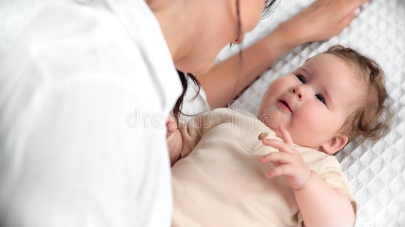 Madre cariñosa y alegre recién nacido feliz con una manta lujosa creando un íntimo momento de unión en un hogar tranquilo y suave almacen de metraje de vídeo
