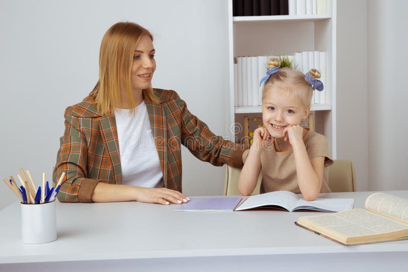 Madre che aiuta poca figlia con compito Concetto di istruzione a domicilio fotografie stock Madre che aiuta poca figlia con compito Concetto di istruzione a domicilio fotografie stock