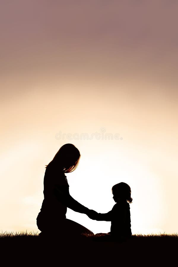 Madre che prega con la sua bambina all'aperto al tramonto fotografia stock