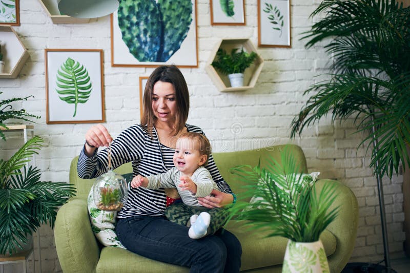 Madre con el bebé año an1 que se sienta en un sofá en casa foto de archivo Madre con el bebé año an1 que se sienta en un sofá en casa foto de archivo