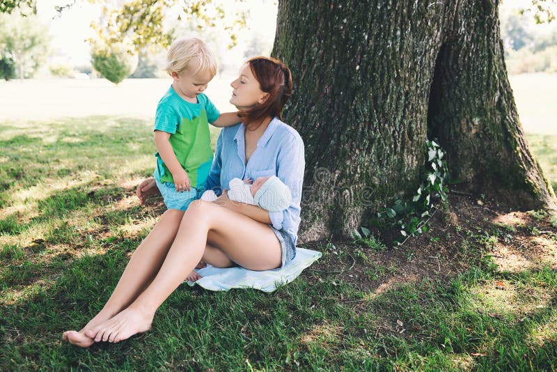 Madre con el bebé recién nacido y un más viejo niño en la naturaleza foto de archivo libre de regalías Madre con el bebé recién nacido y un más viejo niño en la naturaleza foto de archivo libre de regalías