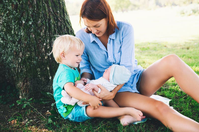 Madre con el bebé recién nacido y un más viejo niño en la naturaleza imagen de archivo libre de regalías Madre con el bebé recién nacido y un más viejo niño en la naturaleza imagen de archivo libre de regalías