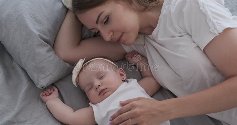 Madre con la hija linda del bebé que duerme en cama