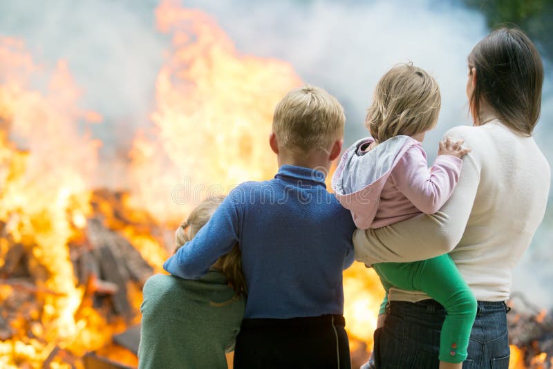 Madre con los niños en el fondo ardiente de la casa