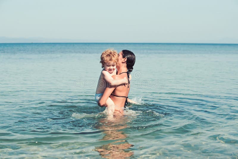 Madre con pequeña nadada del hijo y de la hija en agua de mar en la playa fotos de archivo Madre con pequeña nadada del hijo y de la hija en agua de mar en la playa fotos de archivo