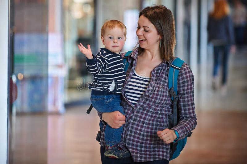 Madre con un bambino di 1 anno che cammina nel centro commerciale La madre tiene il bambino lei armi immagini stock libere da diritti Madre con un bambino di 1 anno che cammina nel centro commerciale La madre tiene il bambino lei armi immagini stock libere da diritti