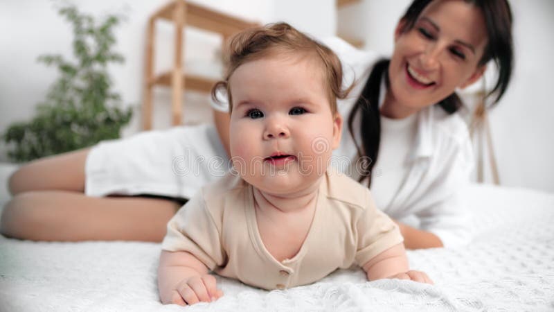 Madre cuidadora que supervisa al niño que desarrolla fuerza en el cuello durante el tiempo del tumor descansando en una blanda man metrajes