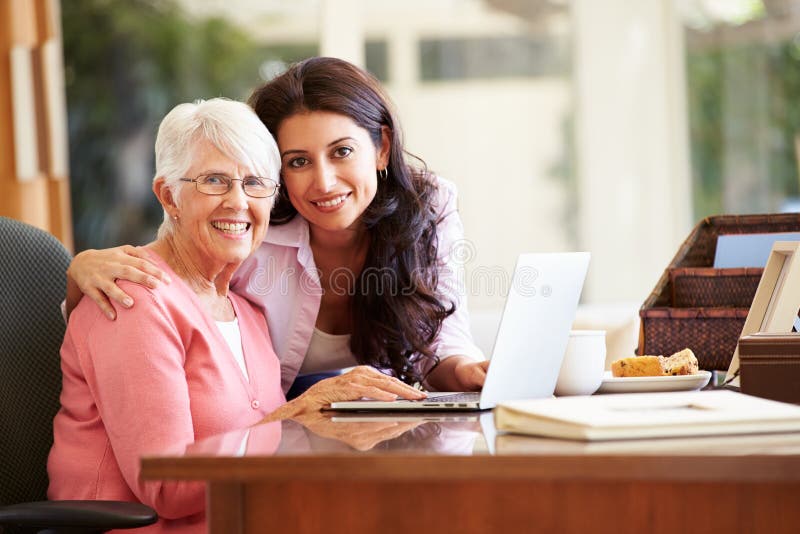Madre d'aiuto della figlia adulta con il computer portatile fotografie stock Madre d'aiuto della figlia adulta con il computer portatile fotografie stock
