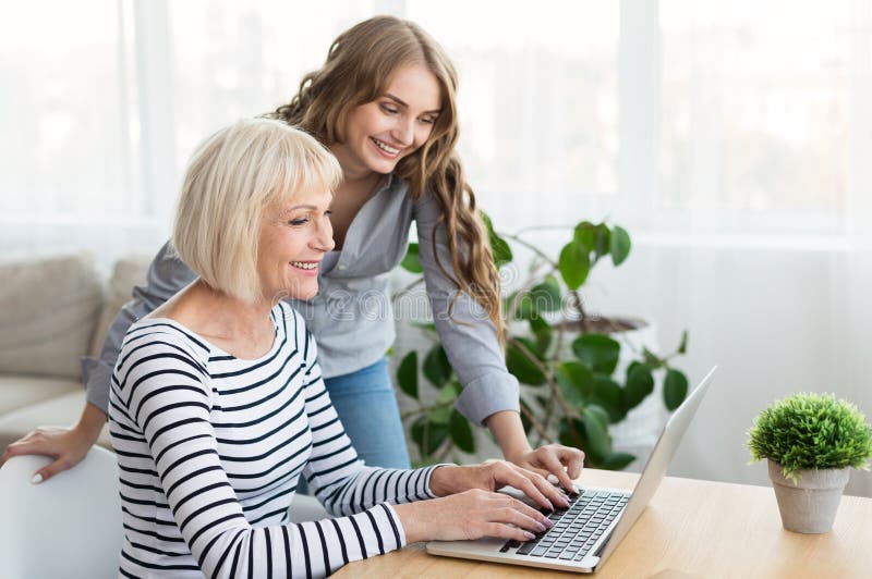 Madre de enseñanza de la hija para utilizar el ordenador portátil en casa fotos de archivo libres de regalías Madre de enseñanza de la hija para utilizar el ordenador portátil en casa fotos de archivo libres de regalías