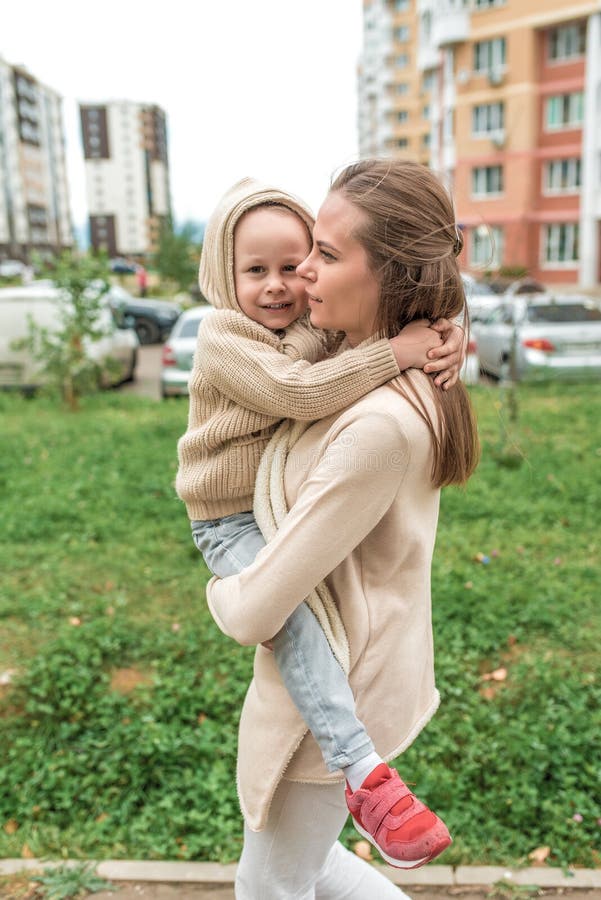Madre de familia con un niño de 4 a 5 años de edad, día de otoño en la ciudad de verano, volviendo a casa en un día frío hierba v fotografía de archivo libre de regalías Madre de familia con un niño de 4 a 5 años de edad, día de otoño en la ciudad de verano, volviendo a casa en un día frío hierba v fotografía de archivo libre de regalías
