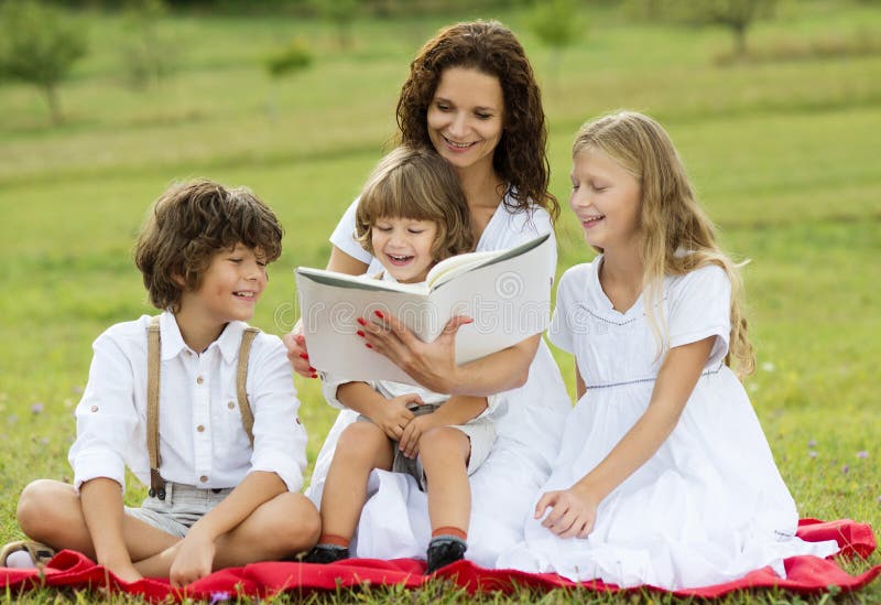Madre e bambini che leggono un libro fotografia stock Madre e bambini che leggono un libro fotografia stock