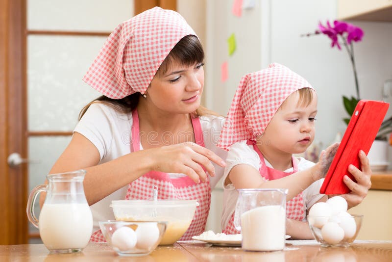 Madre e bambino che preparano pasticceria che esamina libro di cucina fotografia stock Madre e bambino che preparano pasticceria che esamina libro di cucina fotografia stock