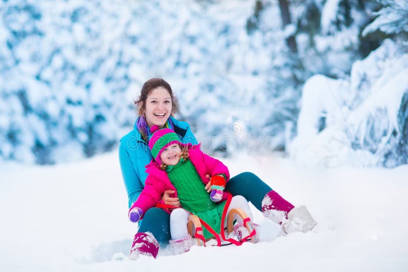 Young mother and little girl enjoying sleigh ride. Child sledding. Toddler kid riding sledge. Children play outdoors in snow. Kids sled in snowy park. Outdoor winter fun for family Christmas vacation. Young mother and little girl enjoying sleigh ride. Child sledding. Toddler kid riding sledge. Children play outdoors in snow. Kids sled in snowy park. Outdoor winter fun for family Christmas vacation.