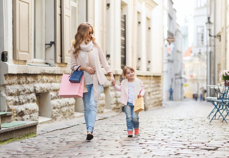 Madre e bambino felici con i sacchetti della spesa in città