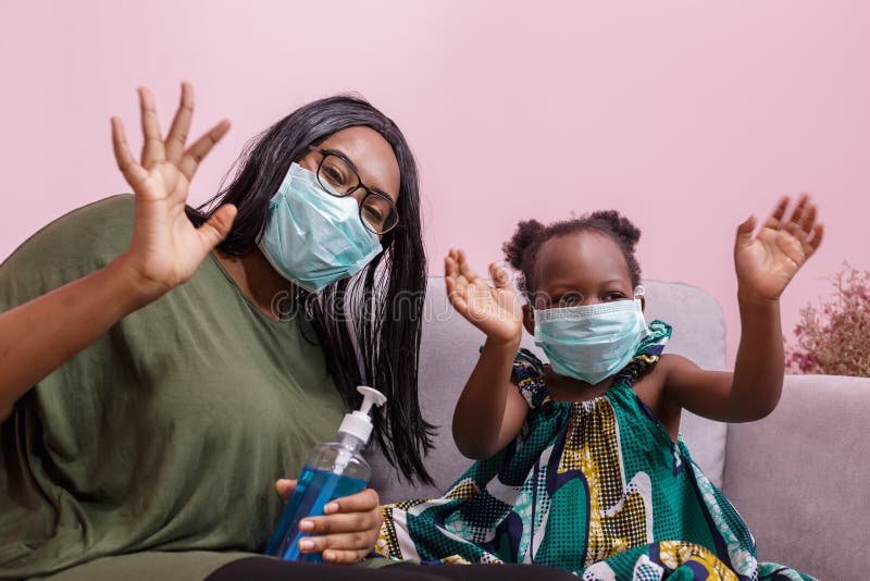 Madre e figlia afro-americane indossano una maschera e si lavano le mani con l'alcol per proteggerle dai germi e dalla vita 1