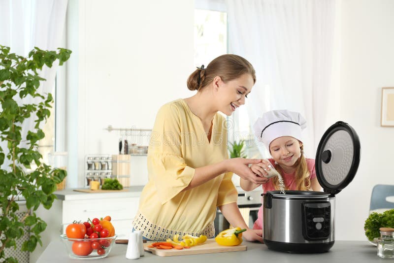 Madre e figlia che preparano alimento con il multi fornello moderno