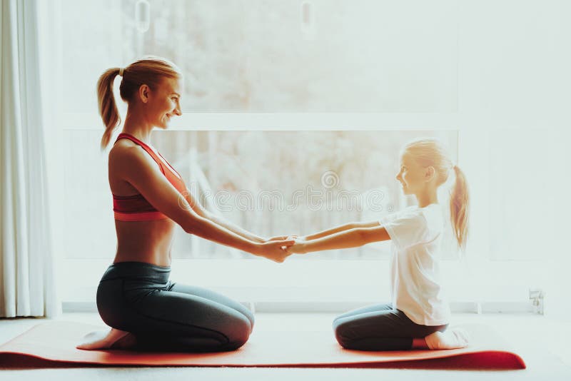 Madre e figlia che si siedono sul tappeto della palestra a casa immagini stock Madre e figlia che si siedono sul tappeto della palestra a casa immagini stock