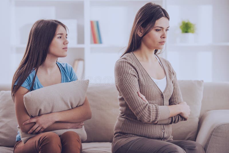 Madre e figlia che si siedono sullo strato dopo il litigio fotografie stock Madre e figlia che si siedono sullo strato dopo il litigio fotografie stock