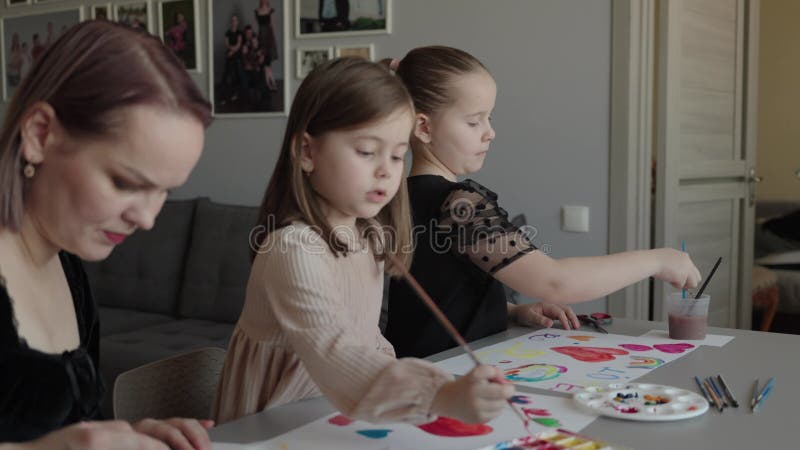 Madre e figlia dipingono cuori e arcobaleni a casa stock footage