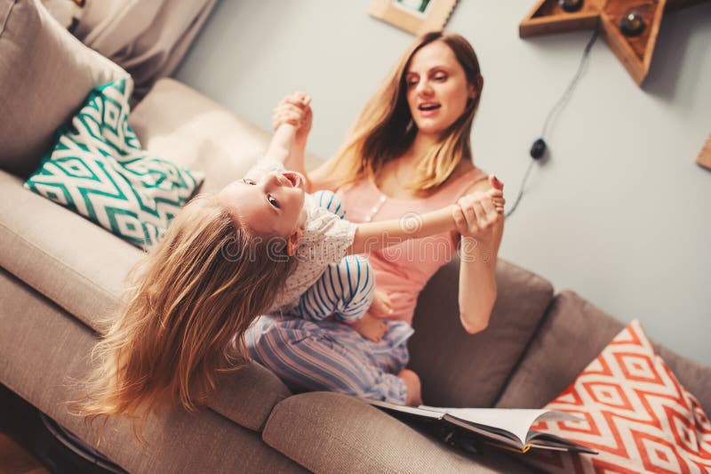 Madre e figlia felici divertendosi a casa sul sofà fotografie stock Madre e figlia felici divertendosi a casa sul sofà fotografie stock