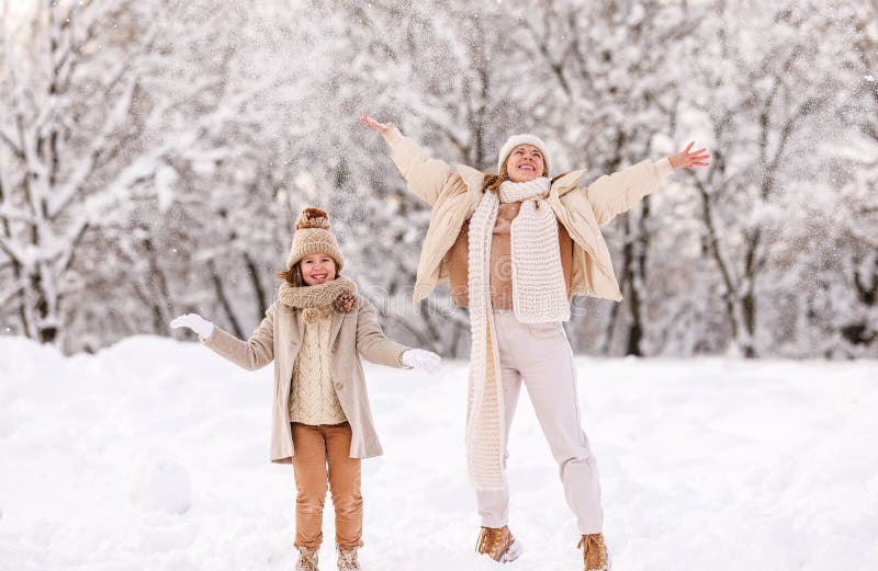 Madre e figlia felici si divertono con la prima neve nel parco invernale nevoso