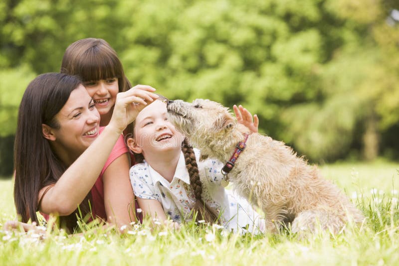 Madre e figlie in sosta con sorridere del cane fotografia stock libera da diritti Madre e figlie in sosta con sorridere del cane fotografia stock libera da diritti