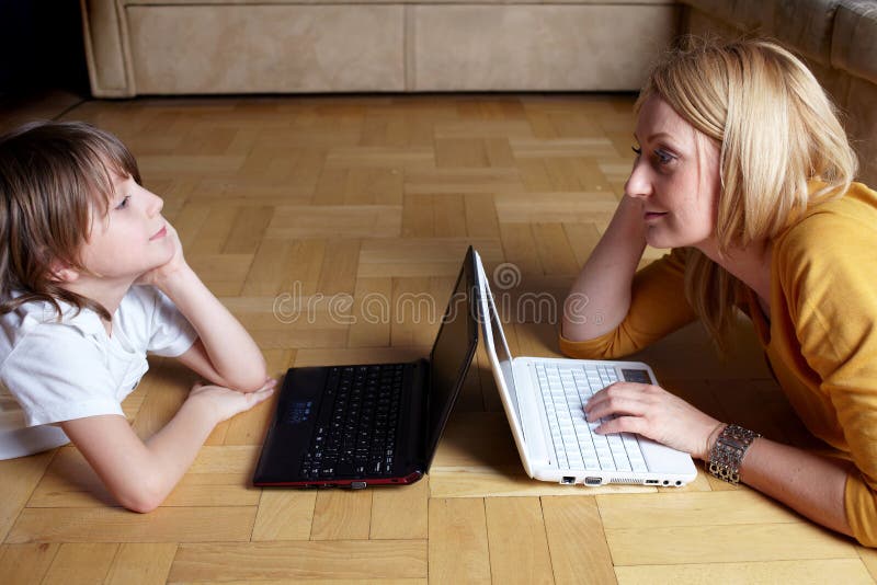 Madre e figlio che lavorano a due piccoli computer portatili fotografia stock Madre e figlio che lavorano a due piccoli computer portatili fotografia stock