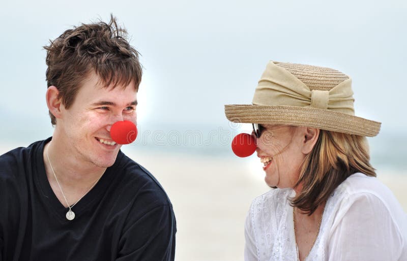 Madre e figlio divertendosi risata celebrando giorno rosso del naso sulla bella festa della spiaggia