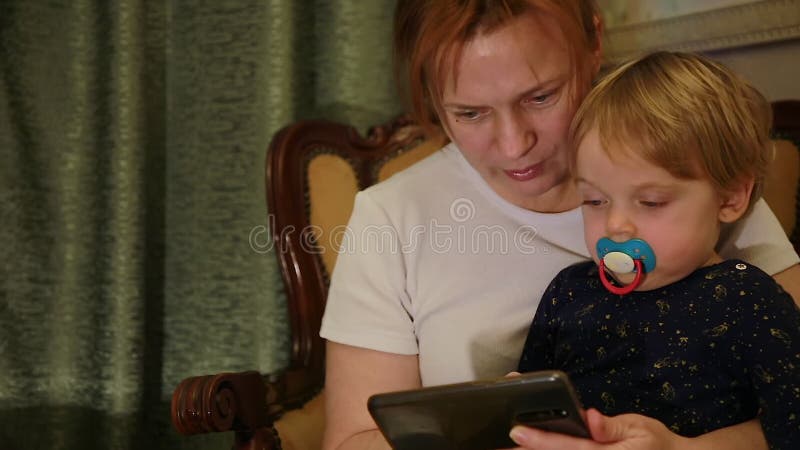 Madre e figlio guardano insieme un video interessante prima di andare a letto sul loro smartphone.