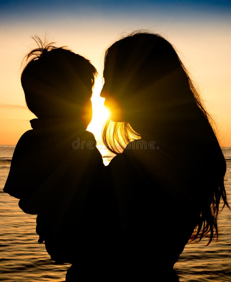 Madre e figlio in un momento profondo di amore durante il tramonto alla spiaggia fotografia stock libera da diritti Madre e figlio in un momento profondo di amore durante il tramonto alla spiaggia fotografia stock libera da diritti